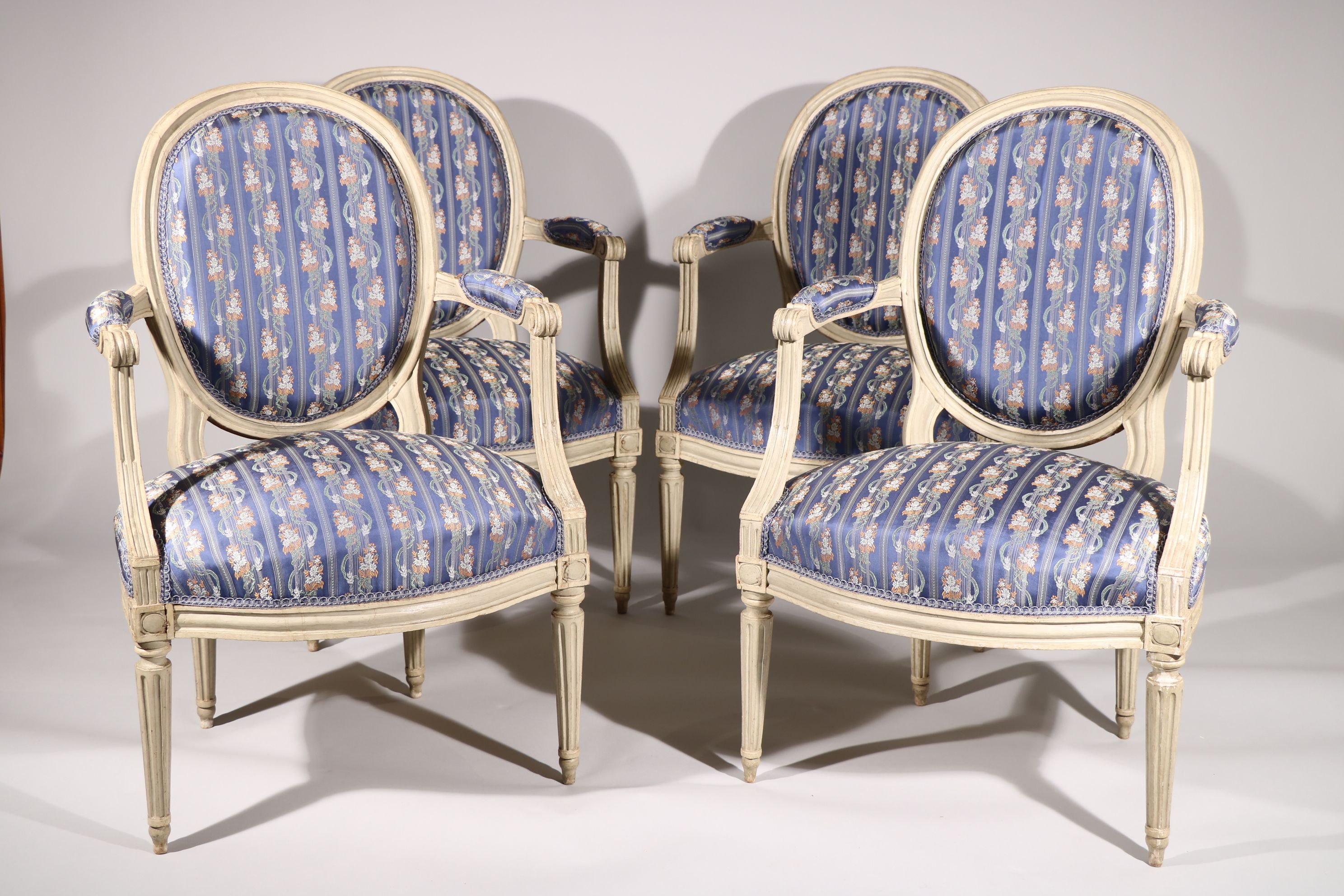 Suite de quatre fauteuils à dossier médaillon en hêtre mouluré et sculpté laqué gris