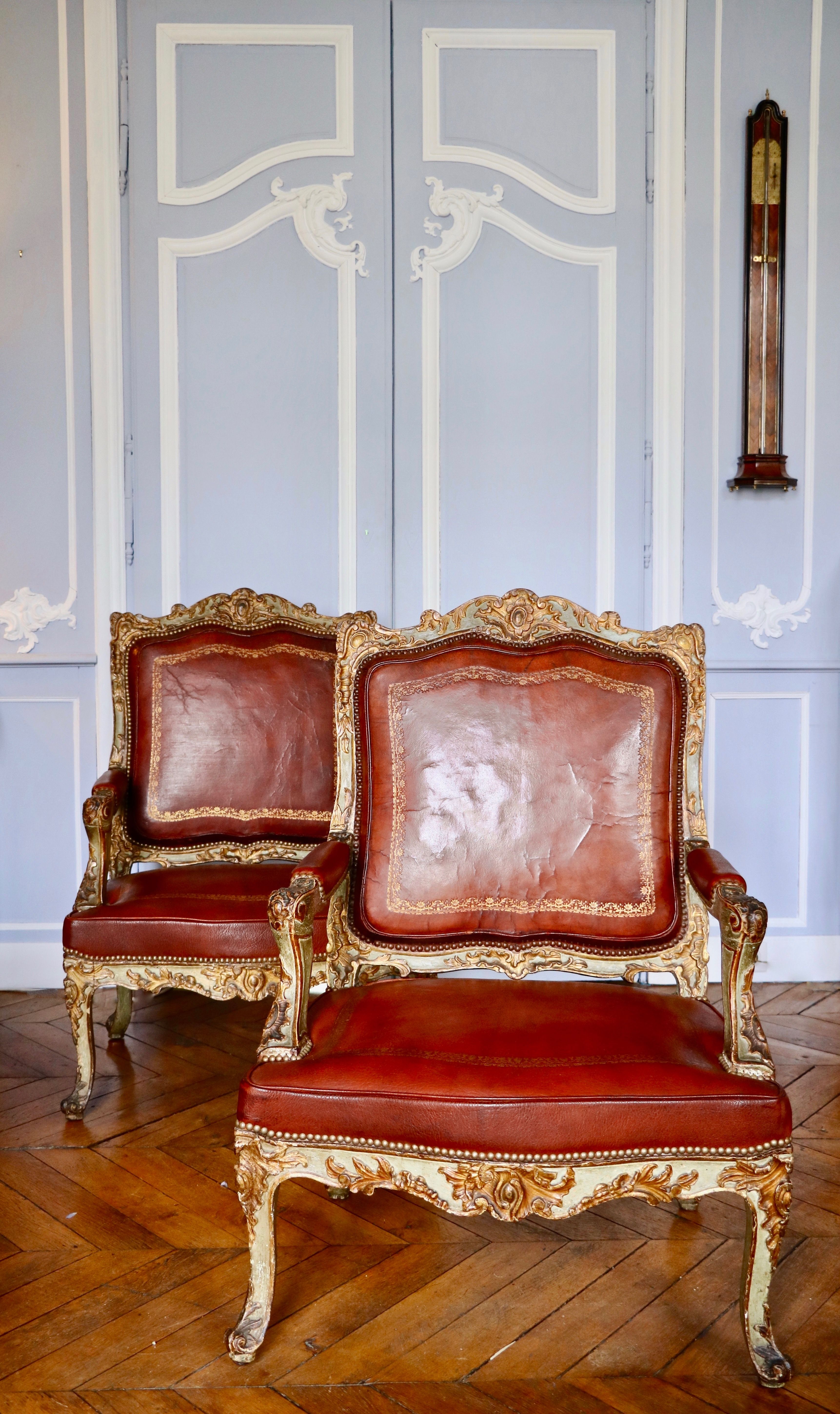 Impressionnante paire de fauteuils à la reine laqués et dorés richement sculptés